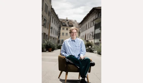 Larissa Waibel sitzt auf einem Sessel mit auf der Strasse und lacht.
